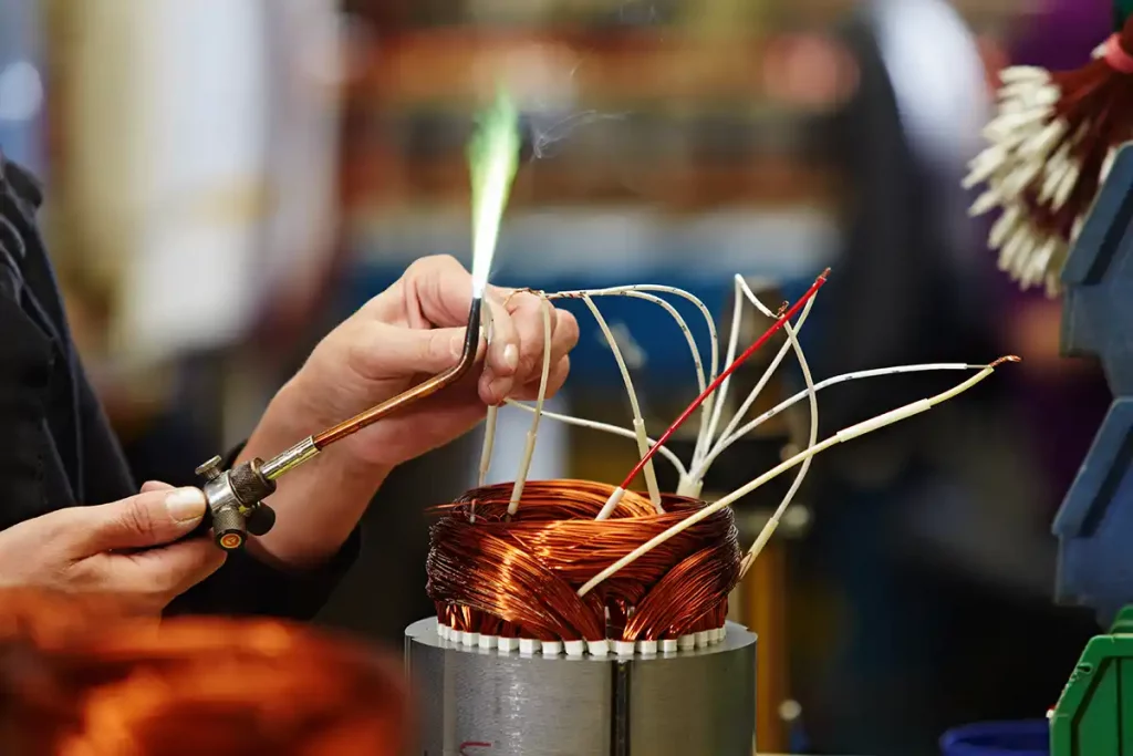 Hand die mit einem Bunsenbrenner einen Elektromotor repariert